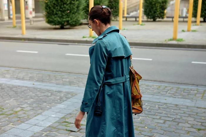 Framed Print : Woman in a blue trench coat walking on a city sidewalk with a yellow shoulder bag Framed Print : Woman in a blue trench coat walking on a city sidewalk with a yellow shoulder bag