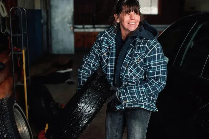 Framed Print : Woman carrying tyre in workshop