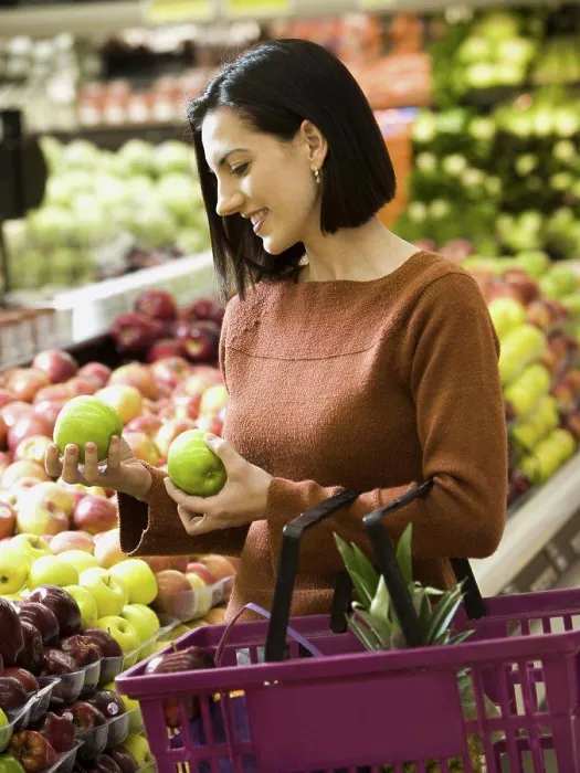 Framed Print : Woman holding green apples at grocery store with shopping basket