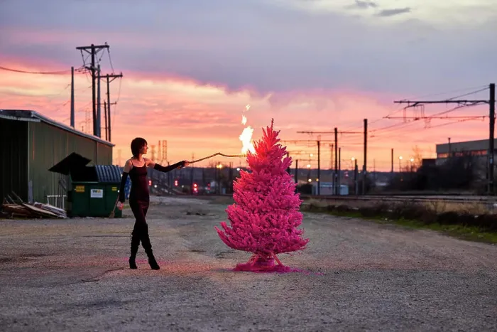 Framed Print : Woman sets fire to pink Christmas tree in industrial area at sunset