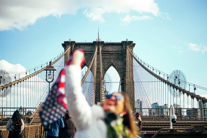 Framed Print : Woman standing on Brooklyn Bridge holding the American flag, New York, United States