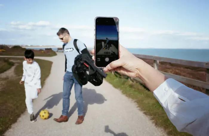 Framed Print : Woman taking pictures of her family playing football with her phone Framed Print : Woman taking pictures of her family playing football with her phone