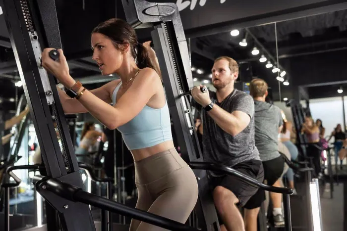Framed Print : Woman training in gym on an exercise machine in group Framed Print : Woman training in gym on an exercise machine in group