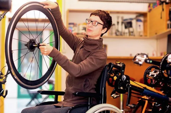 Framed Print : Woman in wheelchair in bicycle repair shop, holding bicycle wheel Framed Print : Woman in wheelchair in bicycle repair shop, holding bicycle wheel