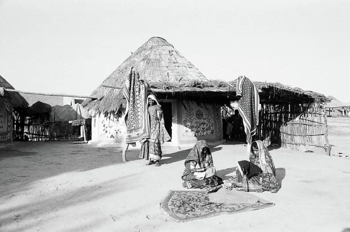 Framed Print : Women in front of round shaped homes bhungas embroidering fabrics
