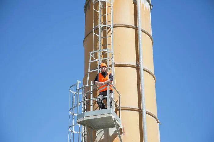 Framed Print : Worker inspecting industrial equipment against a clear blue sky Framed Print : Worker inspecting industrial equipment against a clear blue sky