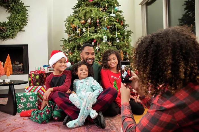 Framed Print : Young Black family taking pictures on mobile phone under Christmas tree