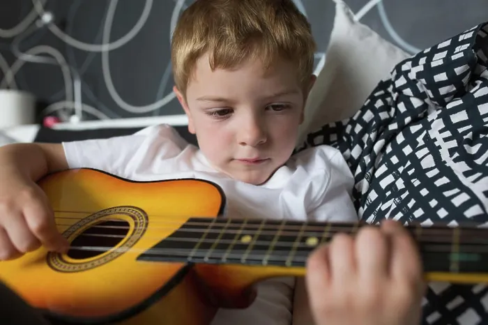 Framed Print : Young blonde boy playing toy guitar Framed Print : Young blonde boy playing toy guitar