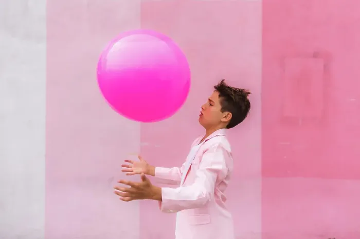 Framed Print : Young boy all pink playing with a ball on the sidewalk in a suit