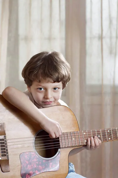 Framed Print : A young boy holding an acoustic guitar