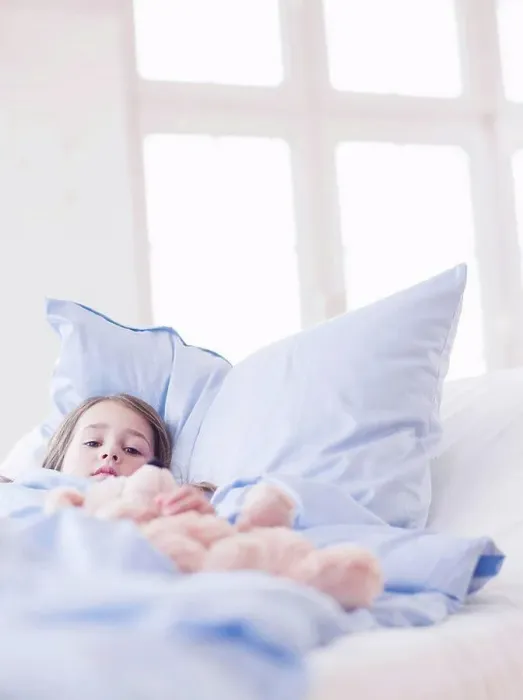 Framed Print : A young girl with brown hair lying in bed holding on to a teddy bear looking at viewer Framed Print : A young girl with brown hair lying in bed holding on to a teddy bear looking at viewer