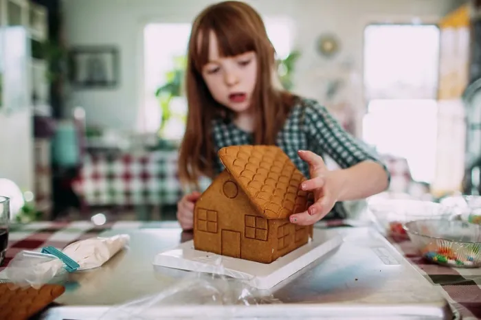 Framed Print : Young girl building a gingerbread house at the dining room table Framed Print : Young girl building a gingerbread house at the dining room table