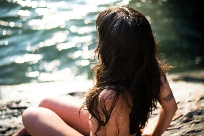 Framed Print : Young Latina Woman sitting by the ocean at golden hour in summertime
