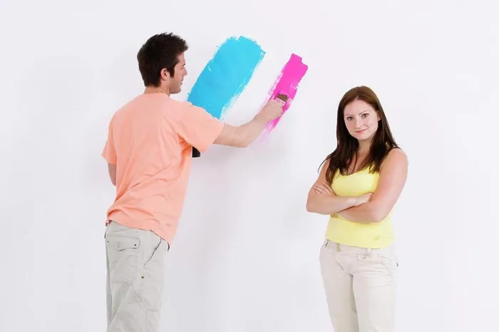 Framed Print : Young man painting a wall with a young woman standing beside him Framed Print : Young man painting a wall with a young woman standing beside him