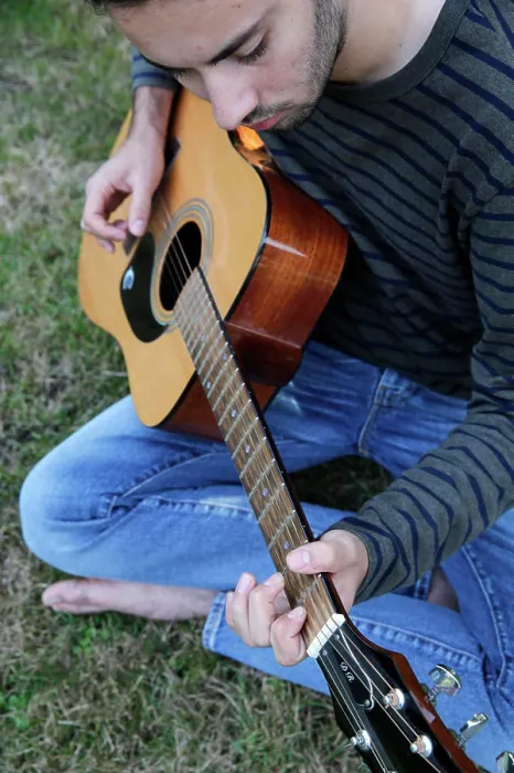 Framed Print : Young man playing a guitar in a garden. France