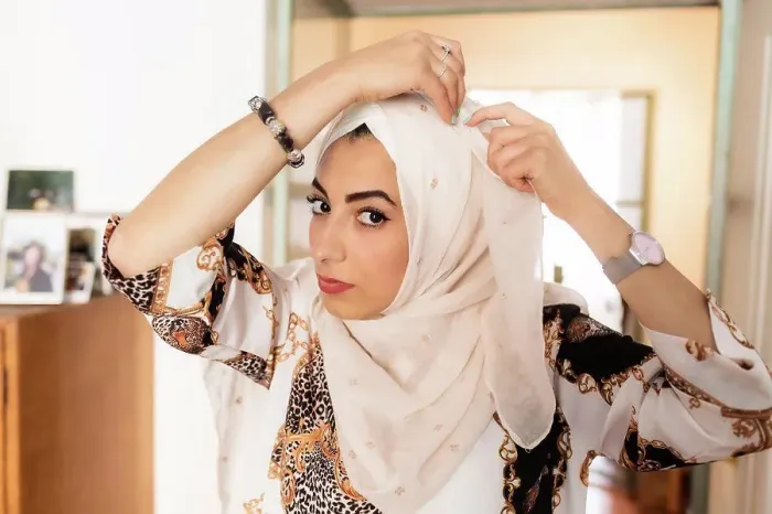 Framed Print : Young muslim woman putting on hijab headscarf