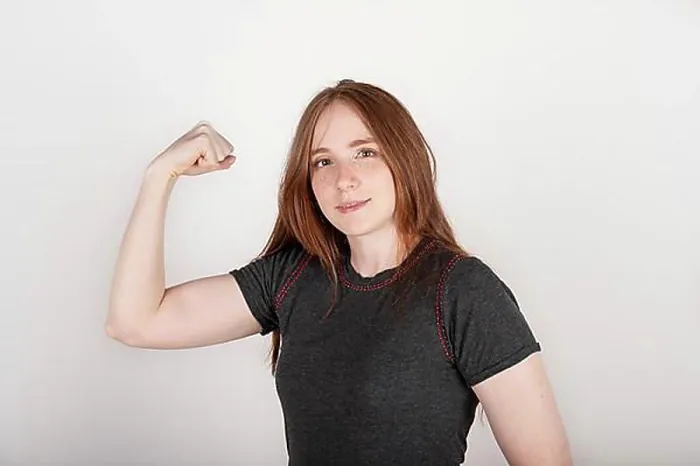 Framed Print : Young red-haired woman proudly showing her bicep. Concept of feminism, girl power Framed Print : Young red-haired woman proudly showing her bicep. Concept of feminism, girl power