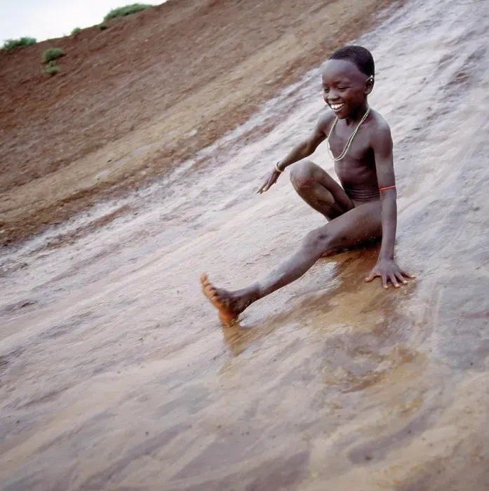 Framed Print : A young Samburu boy enjoys himself on a mudslide