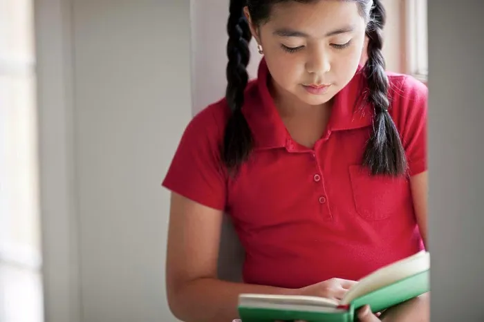 Framed Print : Young schoolgirl reading a book