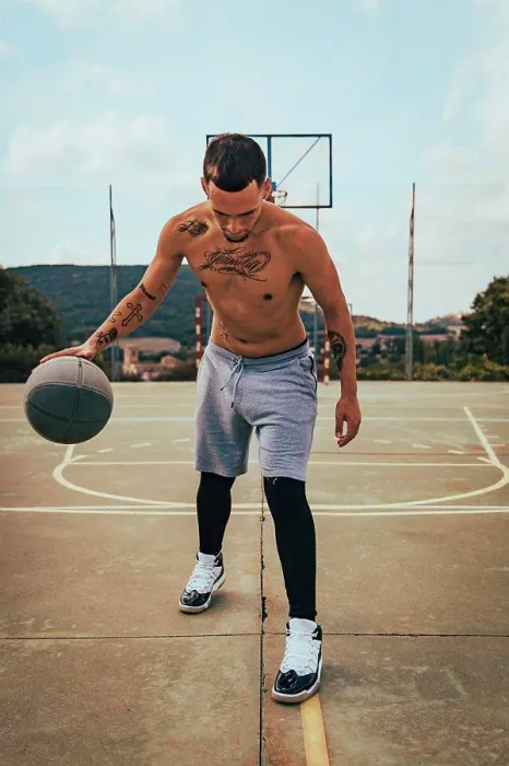 Framed Print : Young tattooed Latino boy playing with a basketball on a court Framed Print : Young tattooed Latino boy playing with a basketball on a court