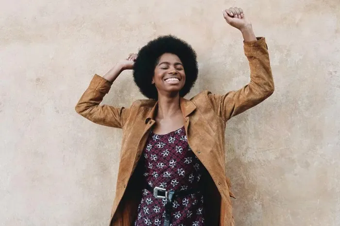 Framed Print : Young woman with afro hair feeling excited against stone wall Framed Print : Young woman with afro hair feeling excited against stone wall