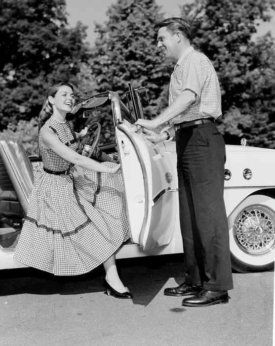 Framed Print : Young woman getting of convertible, young man opening car door