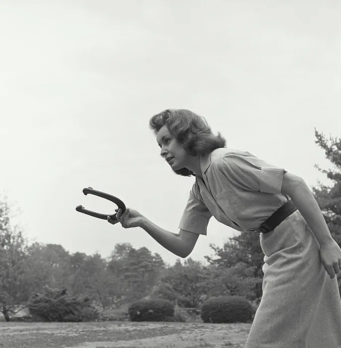 Framed Print : Young woman playing a game of horseshoes Framed Print : Young woman playing a game of horseshoes