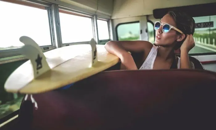 Framed Print : Young woman sitting on a bus with a surfboard