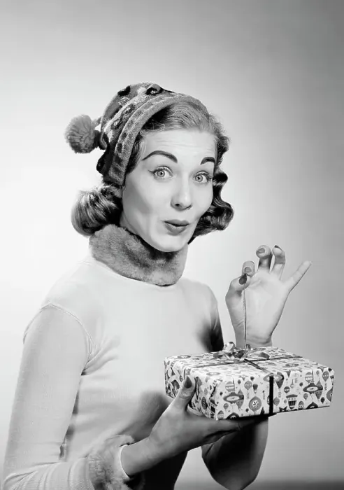 Framed Print : Young woman wearing knit hat opening christmas gift