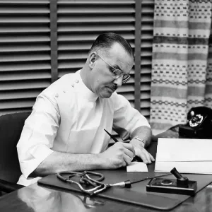 1940S Doctor Sitting At Desk Writing Prescription 1940S Doctor Sitting At Desk Writing Prescription