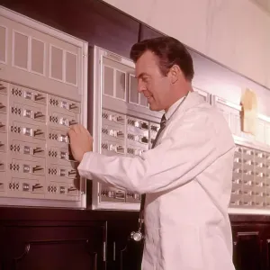 1960s MEDICAL DOCTOR RETRIEVING SUPPLIES FROM SECURE STORAGE 1960s MEDICAL DOCTOR RETRIEVING SUPPLIES FROM SECURE STORAGE
