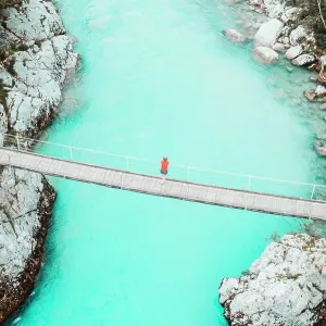 Aerial shot of young woman standing on bridge above whitewater river Aerial shot of young woman standing on bridge above whitewater river