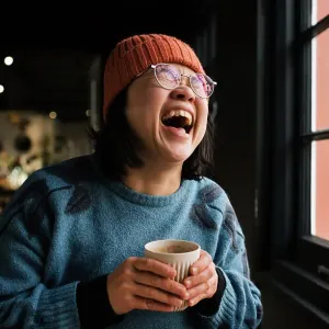 Asian woman laughing having coffee in a cafe Asian woman laughing having coffee in a cafe