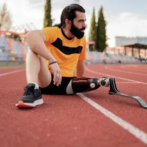 Athlete with prosthetic leg sitting on running track Athlete with prosthetic leg sitting on running track