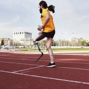 Athlete with prosthetic leg warming up on running track Athlete with prosthetic leg warming up on running track