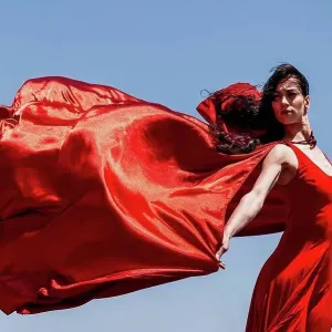 Beautiful female dancer with red scarf looking away against clear sky on sunny day