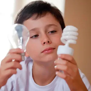 Boy holding energy saving lightbulb (right) and incandescent lightbulb (left) Boy holding energy saving lightbulb (right) and incandescent lightbulb (left)
