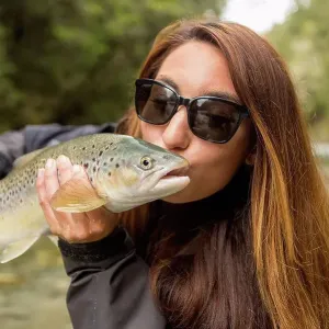 Caucasian woman kissing fish in remote river Caucasian woman kissing fish in remote river