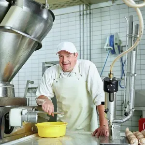 Happy butcher standing by machinery in factory Happy butcher standing by machinery in factory