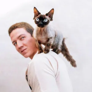 Man looking at cat on shoulder by wall Man looking at cat on shoulder by wall
