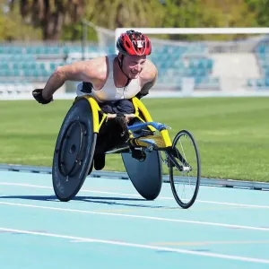 Man racing in wheelchair on track Man racing in wheelchair on track