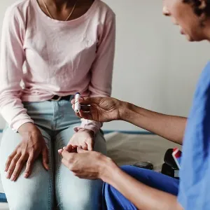 Nurse checking blood sugar of patient in medical examination room Nurse checking blood sugar of patient in medical examination room
