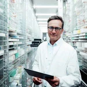 Pharmacist with tablet PC standing in storage room at pharmacy Pharmacist with tablet PC standing in storage room at pharmacy