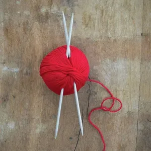 Red ball of wool and knitting needles on wood Red ball of wool and knitting needles on wood