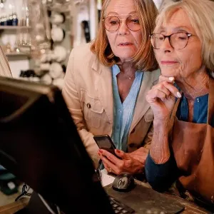 Senior female customer and saleswoman looking at computer monitor in hardware store Senior female customer and saleswoman looking at computer monitor in hardware store
