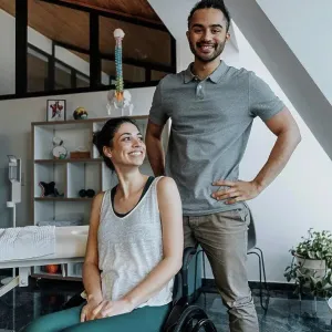 Smiling male physiotherapist standing while female patient sitting on wheelchair Smiling male physiotherapist standing while female patient sitting on wheelchair