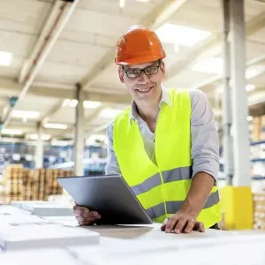 Smiling worker with tablet PC leaning on box in warehouse Smiling worker with tablet PC leaning on box in warehouse