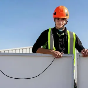 Technician with helmet standing by solar panel Technician with helmet standing by solar panel