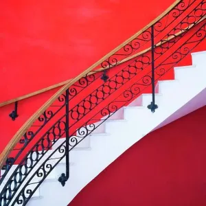 White sweeping staircase set against a red wall in Havana