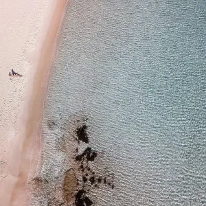 a woman alone on a beach with a clear blue water in Greece a woman alone on a beach with a clear blue water in Greece
